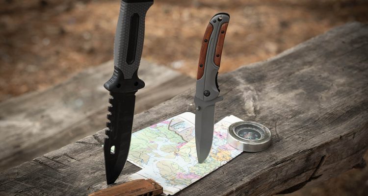 Hunting knife, compass and map on a wooden table in the forest. Concept of adventure
